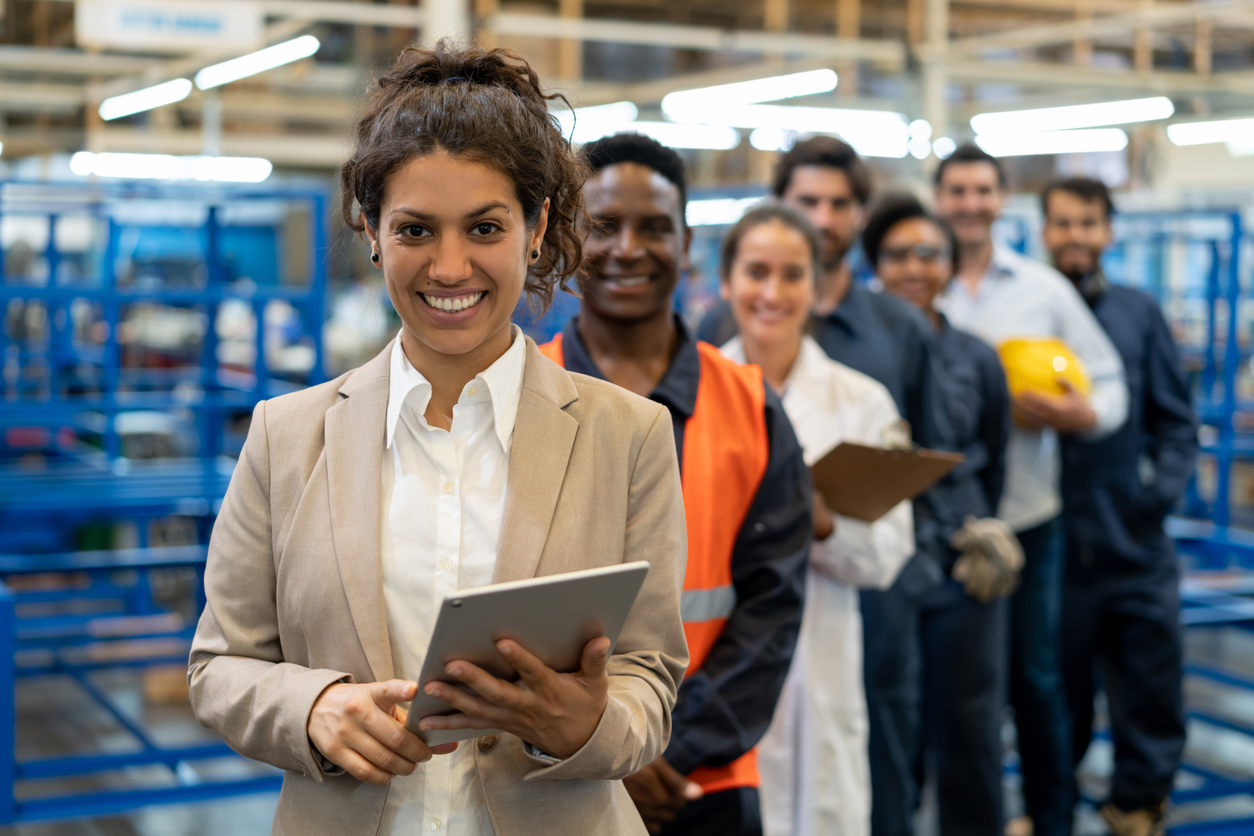 smiling-woman-with-tablet-and-different-people-in-different-functions-standing-behind-her-smiling